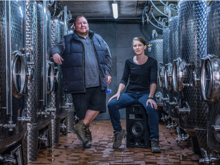 Holger Breit (staand) en zijn vrouw (zittend) tussen de wijnvaten in de wijnkelder.