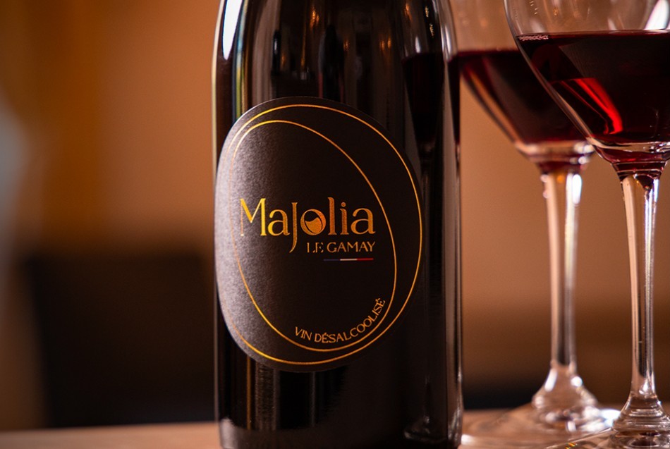 Een fles wijn met daarnaast twee gevulde glazen - Le Majolia - gede-alcoholiseerde wijn uit de Beaujolais